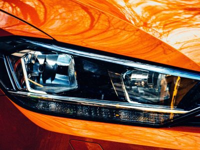 A closeup shot of the right headlight of an orange modern car